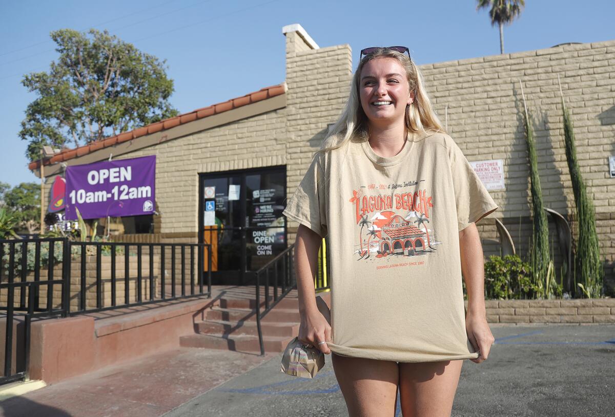 A woman wears a tan T-shirt outside a Taco Bell restaurant