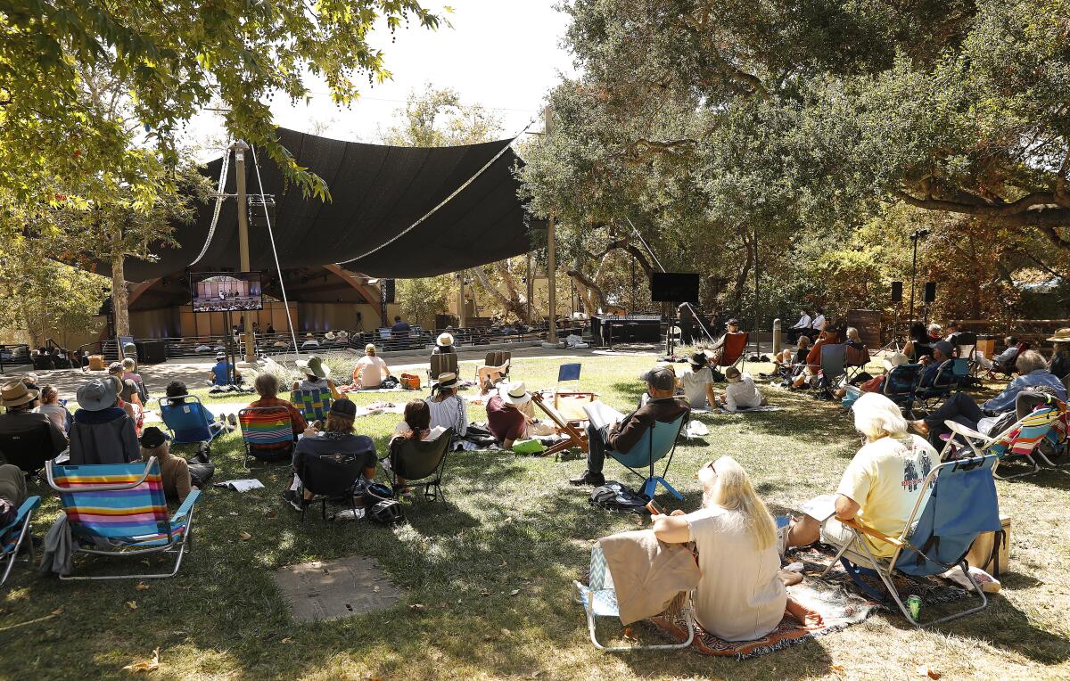 People sit in lawn chairs watching a concert