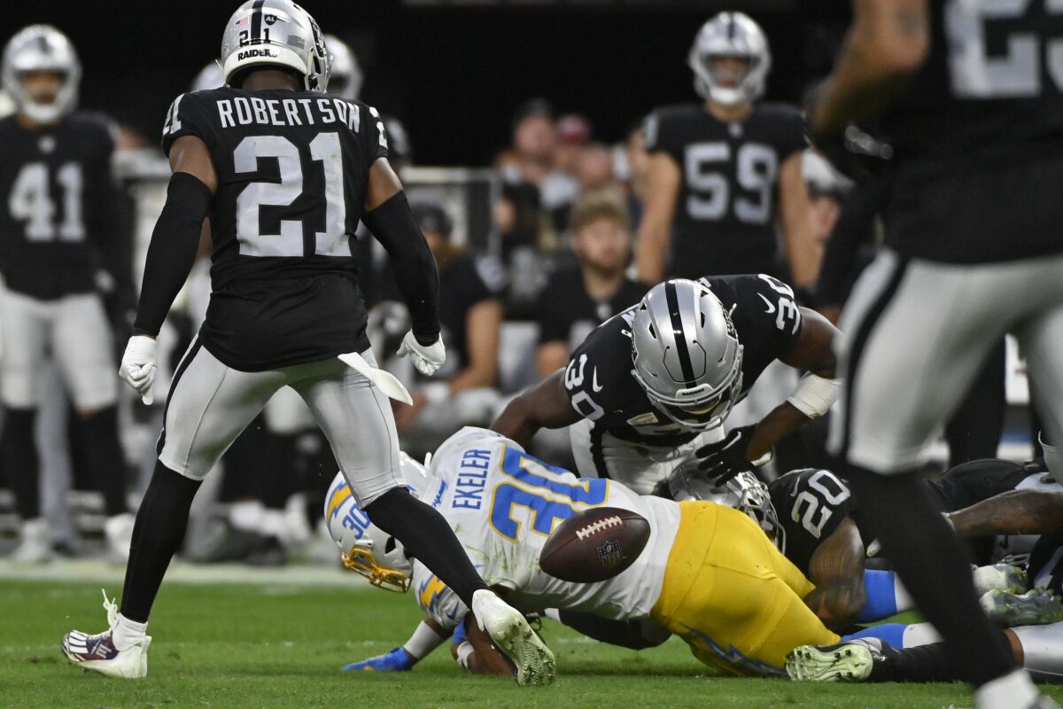 The Chargers' Austin Ekeler (30) fumbles between Raiders Duron Harmon (30) and Amik Robertson (21) in the second half.