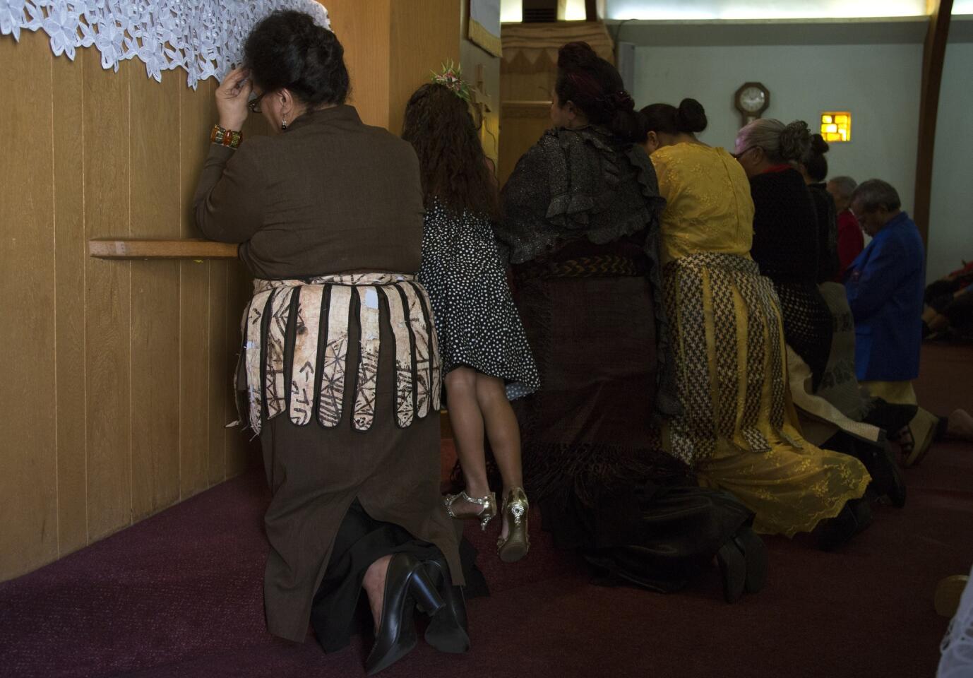 Members of the congregation kneel in prayer at the front of the Tongan United Methodist Church during the Sunday service.