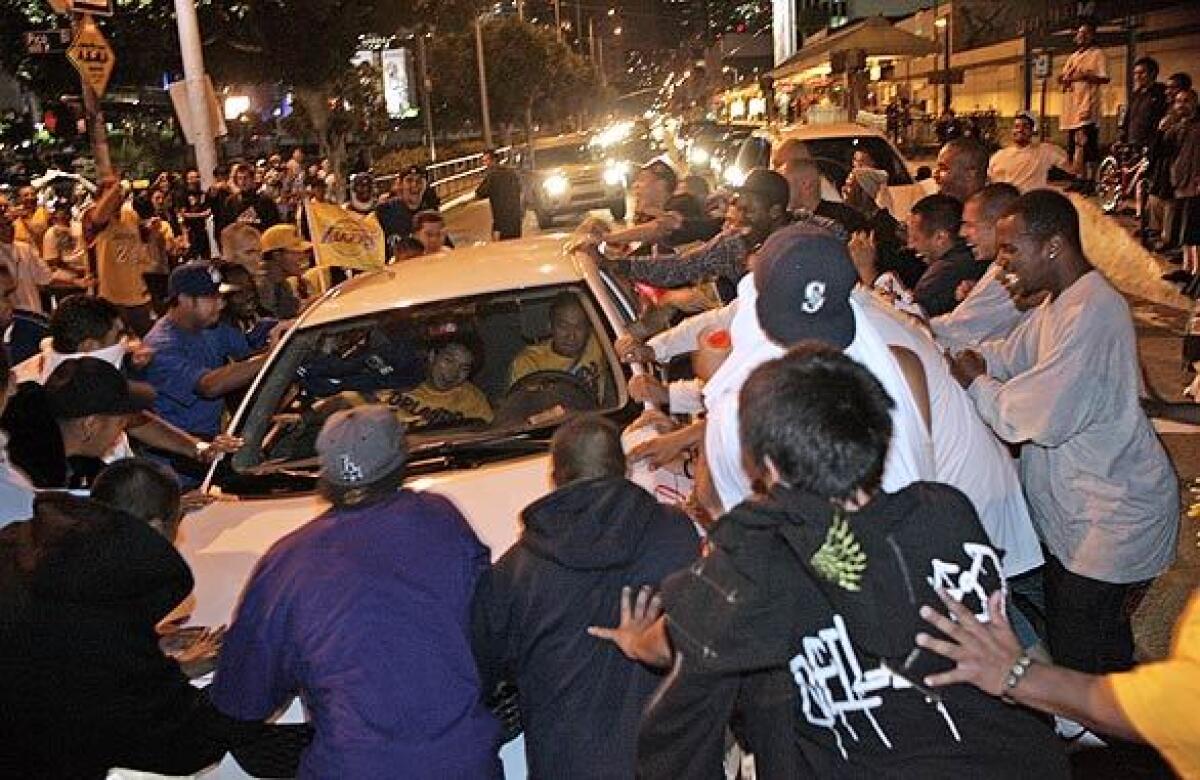 A group of men rock a car with a Lakers flag