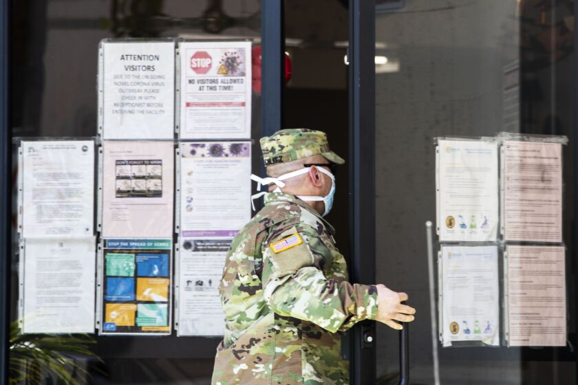 HOLLYWOOD, CA - APRIL 24: National Guard Sgt. Joseph Schlitz enters the Hollywood Premier Healthcare Center, which has seen 25 cases among staff and 29 among residents on Friday, April 24, 2020 in Hollywood, CA. Guard medical teams are augmenting staff the the facility. (Brian van der Brug / Los Angeles Times)