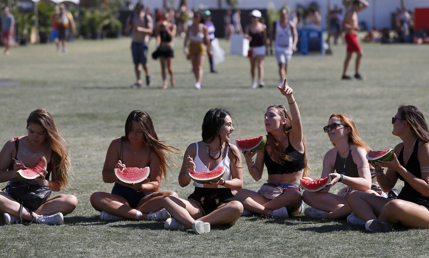 A group of girls keeps cool with wedges of watermelon as they watch a performance by Jamaican reggae artist Chronixx at the Coachella Music and Arts Festival.