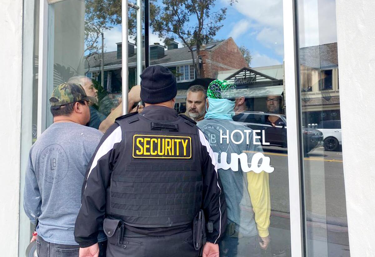 A security guard and other people stand at the entrance to a hotel