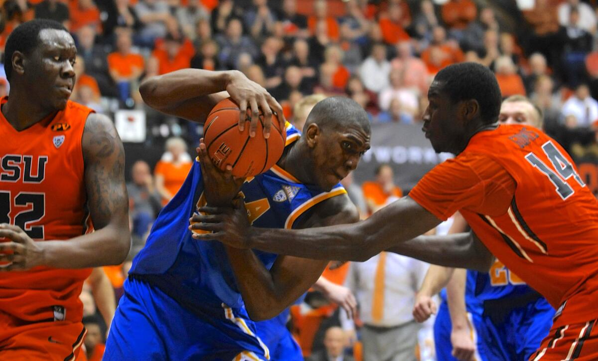 UCLA forward Kevon Looney protects the ball against Oregon State's Jamal Reid (32) and Daniel Gomis (14) after getting a rebound in their game Thursday night.