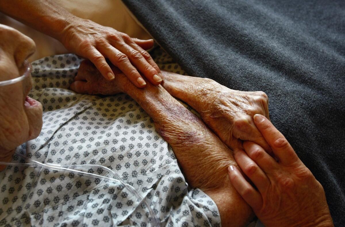 Hospice volunteers in Lakewood, Colo., caress the hands of a terminally ill patient.
