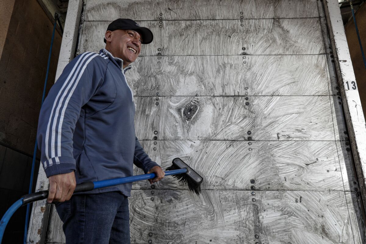 Arnulfo Gonzalez washes a piece of his artwork from the back of his truck.