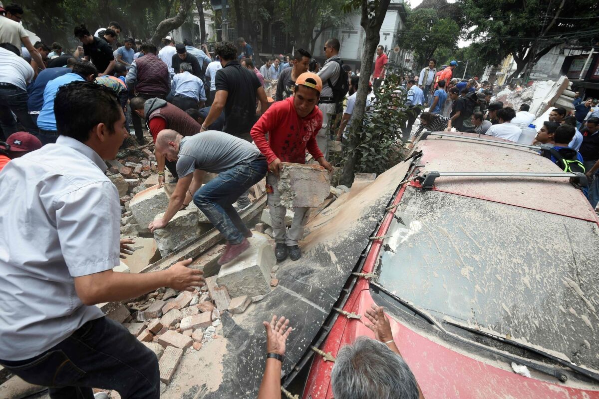 People in Mexico City remove debris after a building collapsed in a powerful earthquake on Tuesday.