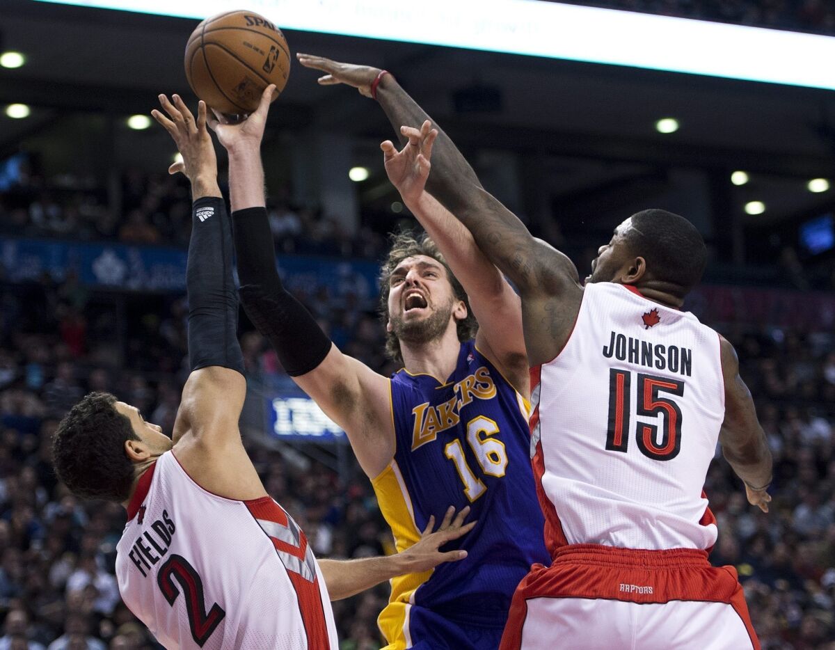 Lakers power forward Pau Gasol has his shot challenged by Raptors center Amir Johnson and forward Landy Fields in the second half.