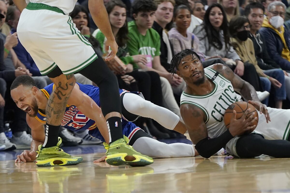 Golden State Warriors guard Stephen Curry, left, reacts after going for a loose ball next to Boston Celtics guard Marcus Smart during the first half of an NBA basketball game in San Francisco, Wednesday, March 16, 2022. (AP Photo/Jeff Chiu)