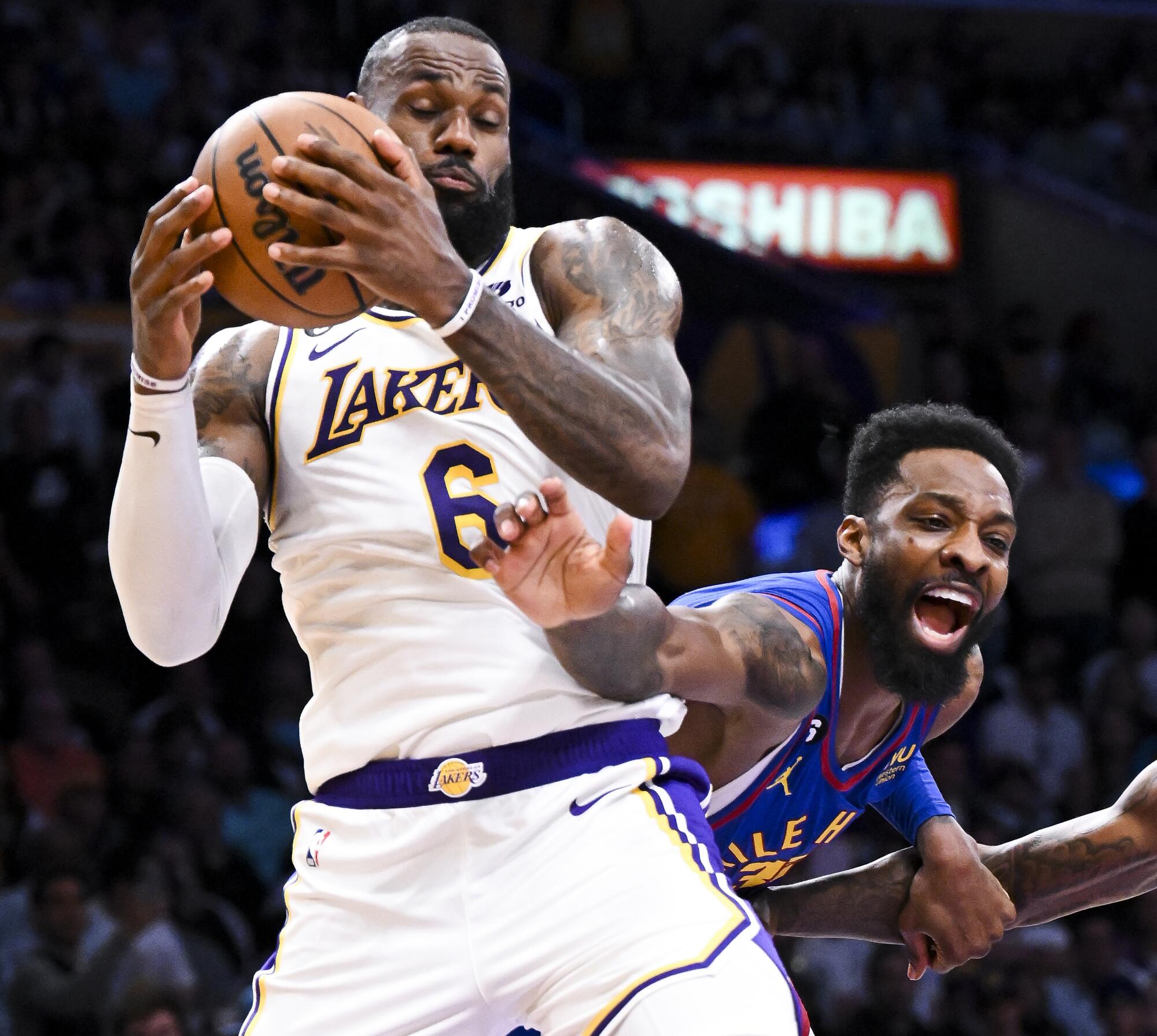 Lakers forward LeBron James, left, grabs a rebound in front of Nuggets forward Jeff Green.