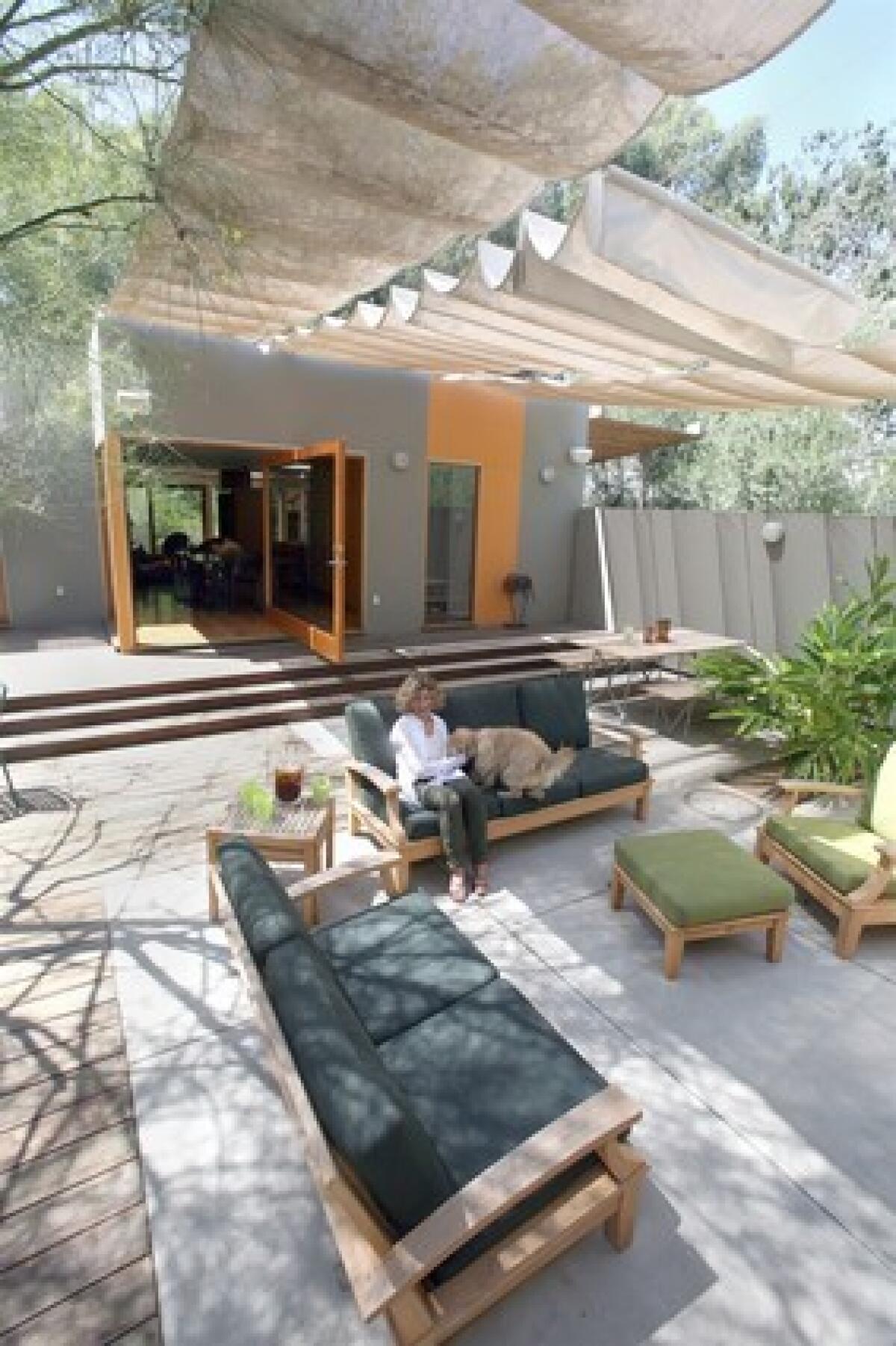 Sharon Bowman plays with her dog in her outdoor room in Los Angeles. When Bowman and husband Joe Fineman wanted to remodel their house, Culver City architect Lorcan OHerlihy suggested turning what had been the living room into an alfresco space. Ipe wood steps now lead from the house to a patio floor of concrete pavers and wood, all shaded by a retractable soft ceiling.
