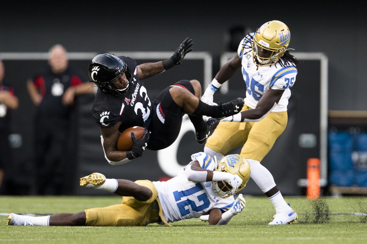 UCLA defensive backs Elijah Gates (12) and Carl Jones (35) bring down Cincinnati running back Gerrid Doaks during the first half of the Bruins' season-opening loss Thursday.