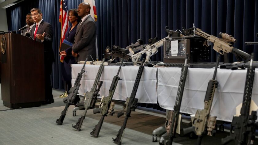 California Atty. Gen. Xavier Becerra, at lectern, and L.A. County Dist. Atty. Jackie Lacey, second from right, announced Wednesday that special agents had seized 28 guns from the home of a man who is legally barred from owning firearms.