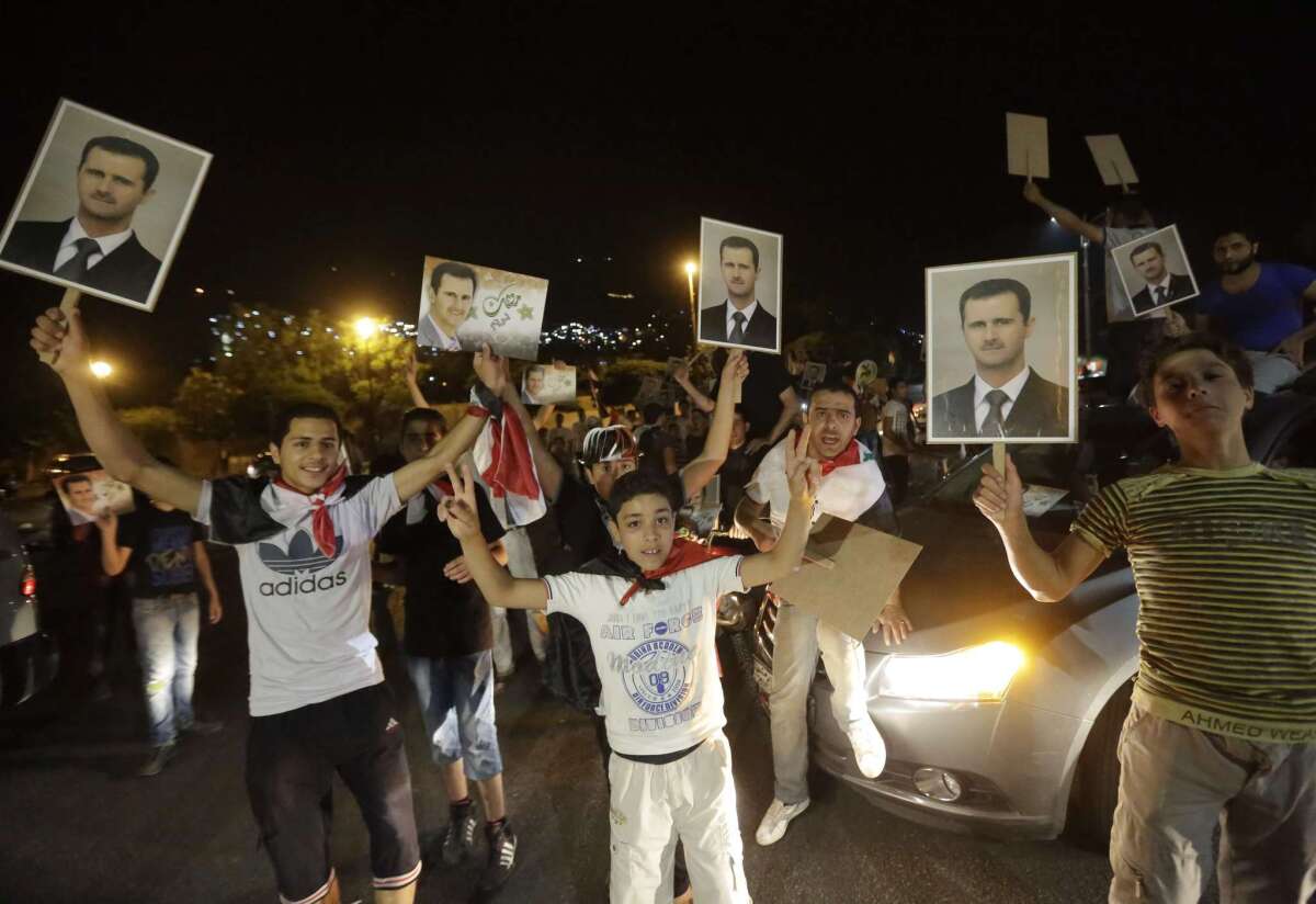 Syrians hold pictures of President Bashar Assad as they celebrate in Damascus after Assad was proclaimed the winner of the country's presidential election.