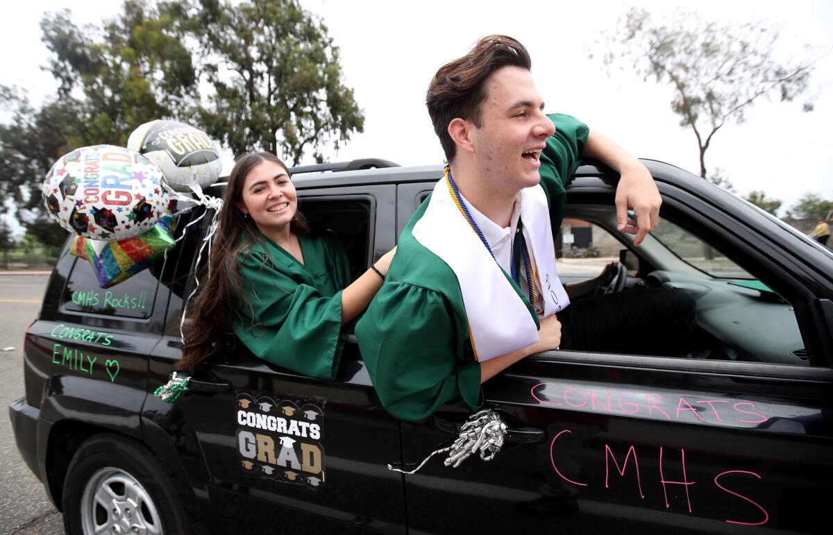 Costa Mesa High School graduates hang out of car windows as they pass Estancia High School.