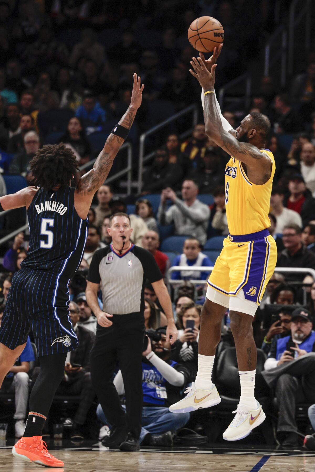 El alero de los Lakers de Los Ángeles LeBron James lanza el balón sobre el alero del Magic de Orlando Paolo