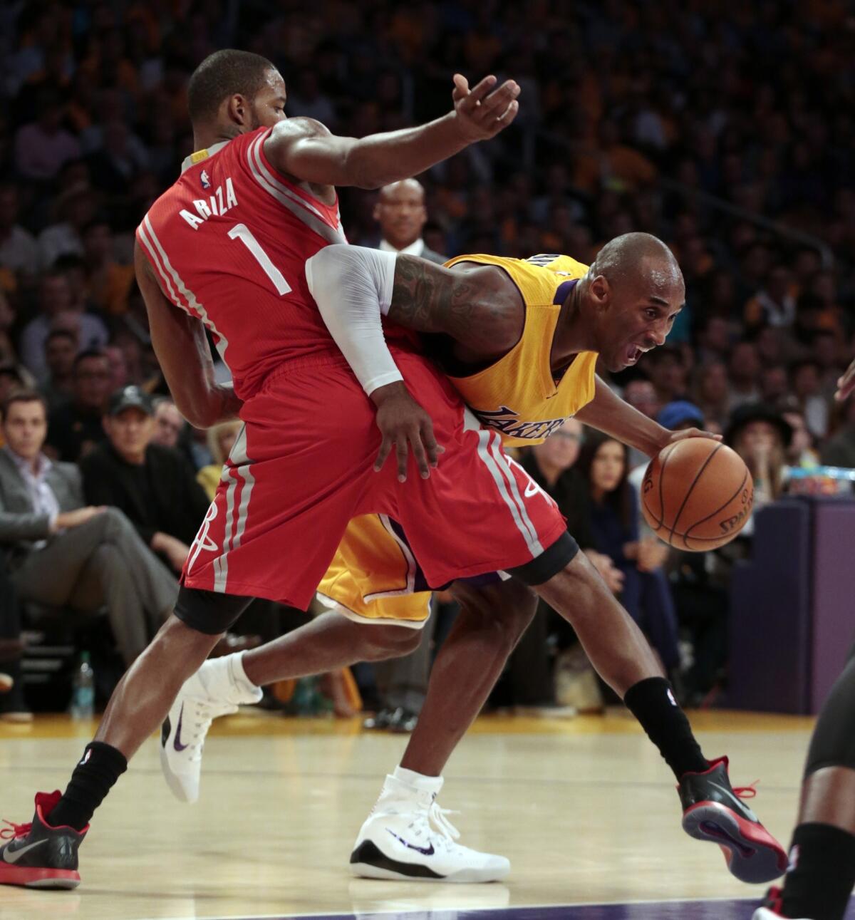 Kobe Bryant tries to work around the defense of Houston's Trevor Ariza during the first quarter of the Lakers' season opener against the Rockets at Staples Center.