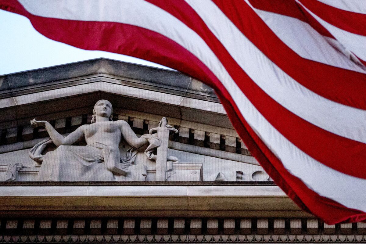 FILE - An American flag flies outside the Department of Justice in Washington, March 22, 2019. A Temple University physicist who was charged with sharing scientific technology with China only for the case to collapse before trial and be dismissed by the Justice Department is asking a federal appeals court to reinstate his lawsuit against the FBI agent who investigated him. Lawyers for Xiaoxing Xi and his wife say in a brief filed Monday with a Philadelphia-based appeals court that a judge erred last year when he dismissed their claims for damages. (AP Photo/Andrew Harnik, File)