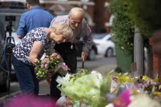 An elderly couple leaves a floral tribute near the scene in Hart Street, where three children died and eight were injured in a knife attack during a Taylor Swift event at a dance school on Monday, in Southport, England, Tuesday, July 30, 2024. (James Speakman/PA via AP)
