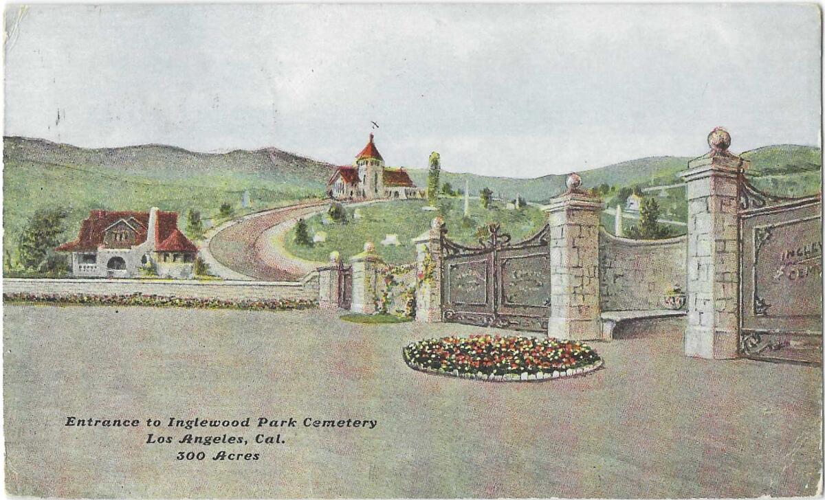 Red-roofed buildings sit on green hills behind the gates of a cemetery