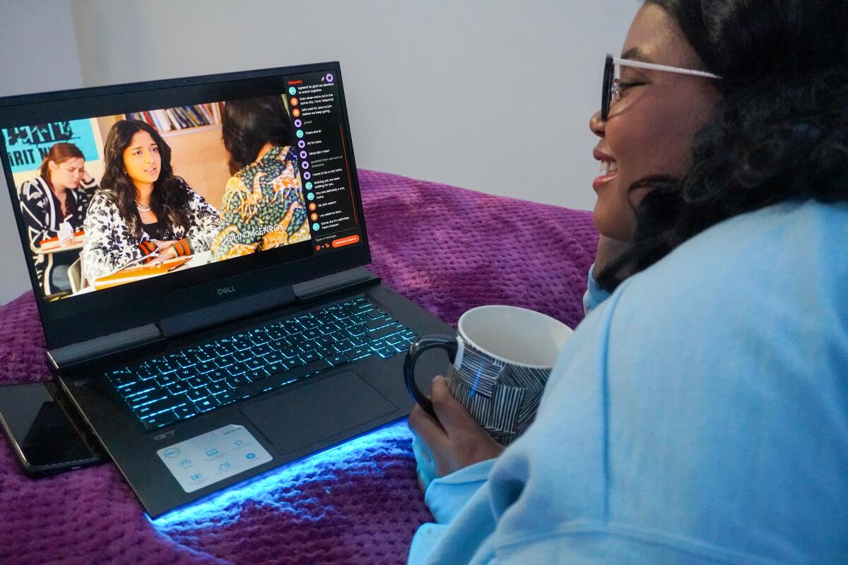 A young woman watches a show on her laptop while using Teleparty.