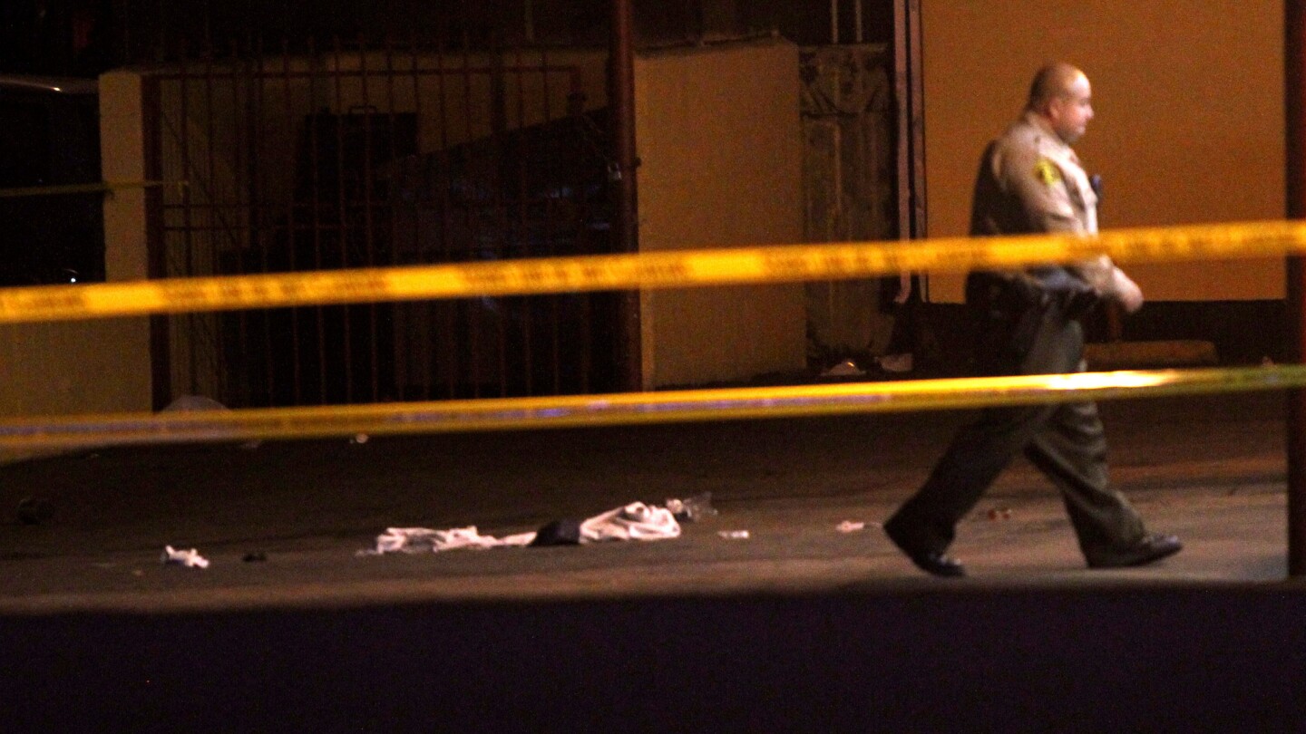 A Los Angeles County sheriff's deputy walks past part of the Tam's Burgers parking lot, where the hit-and-run occurred.