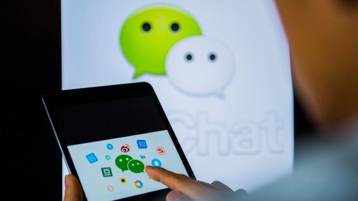 A man uses the WeChat app on an Apple iPad Mini 