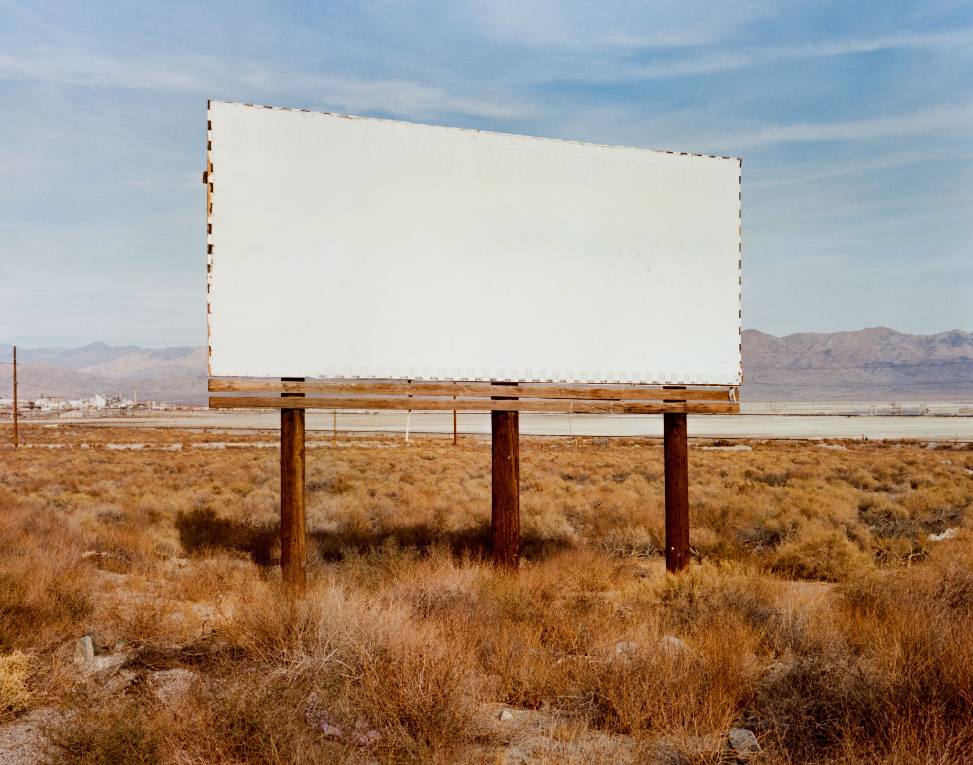 A blank billboard stands in the middle of a desert landscape. 