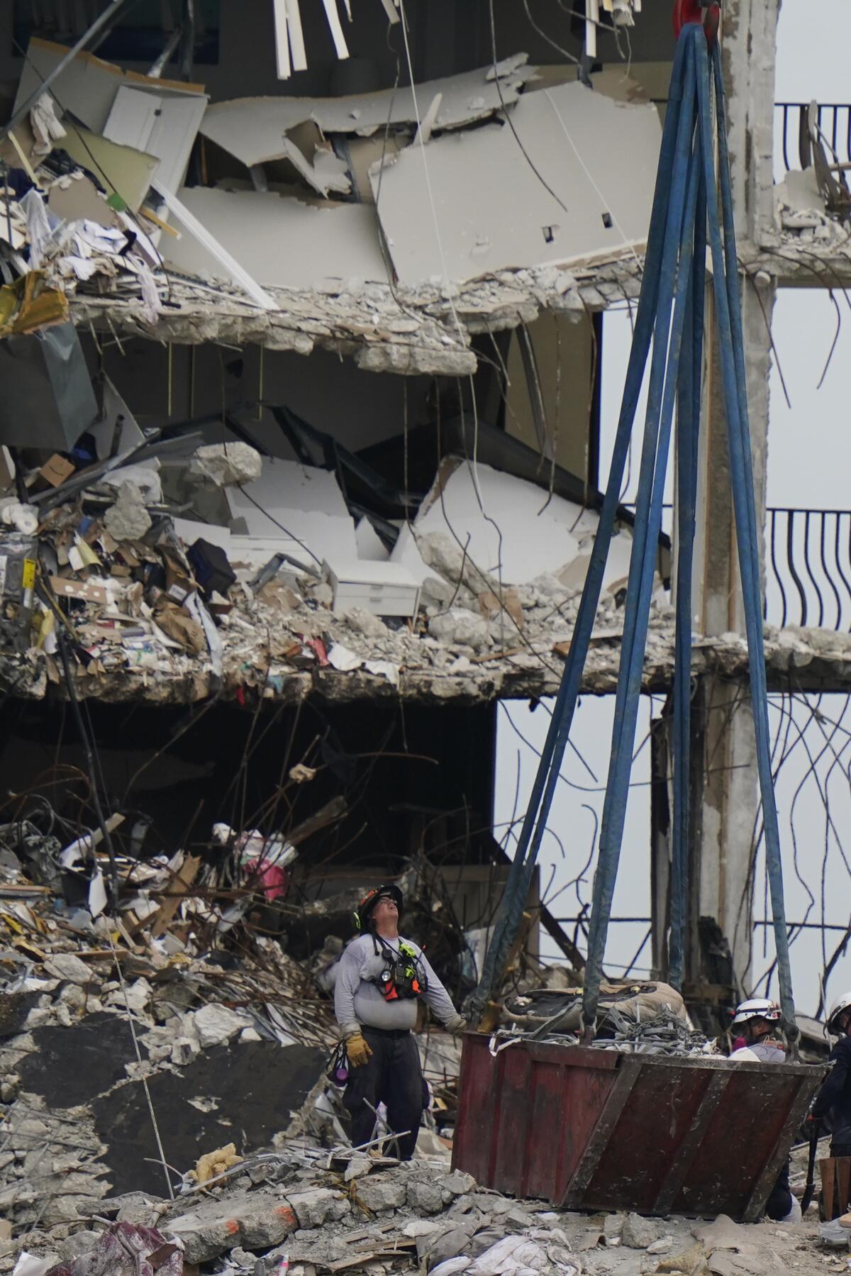 A crane prepares to remove a load of debris at the collapsed building