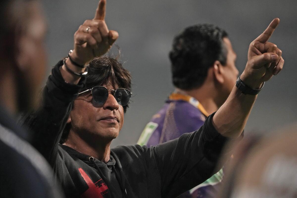 Bollywood superstar Shah Rukh Khan raises his hands during a cricket game.