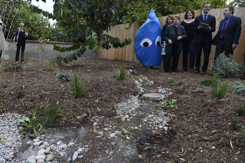 L.A. County Supervisor Sheila Kuehl, Mayor Eric Garcetti and conservation advocate Andy Lipkis of TreePeople stand with others and watch as water is released electronically from a newly installed 500 liter water cistern into a "rain garden" for replenishing groundwater on Nov. 4.