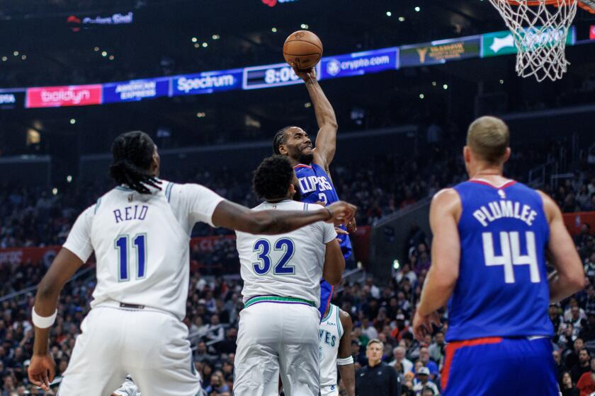 LOS ANGELES, CA - FEBRUARY 12, 2024: LA Clippers forward Kawhi Leonard (2) leaps through the key for a slam dunk in front of Minnesota Timberwolves center Karl-Anthony Towns (32) and Minnesota Timberwolves center Naz Reid (11)in the first half at Crypto.com Arena on February 12, 2024 in Los Angeles, California.(Gina Ferazzi / Los Angeles Times)