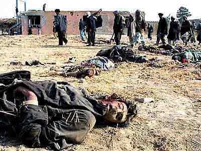 Northern Alliance fighters walk through a yard littered with bodies of pro-Taliban forces.