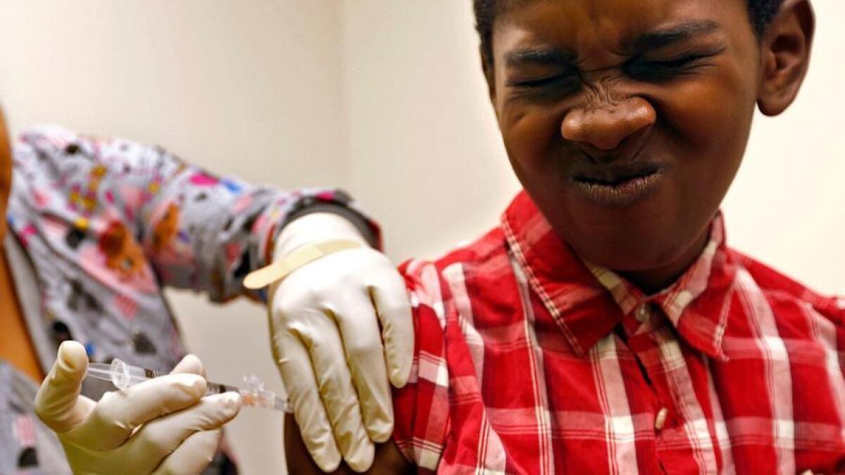 Desmond Sewell, de 12 años, recibe sus vacunas por parte de la asistente médica Jessica Reyes en el Centro de Salud y Bienestar Infantil Lou Colen, en Mar Vista.