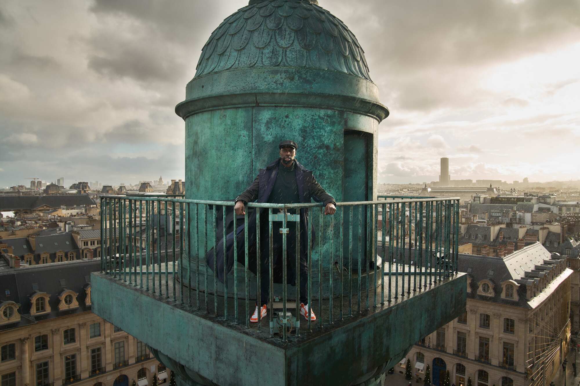 Assane Diop stands with his hands on the fencing of the ledge of a building.