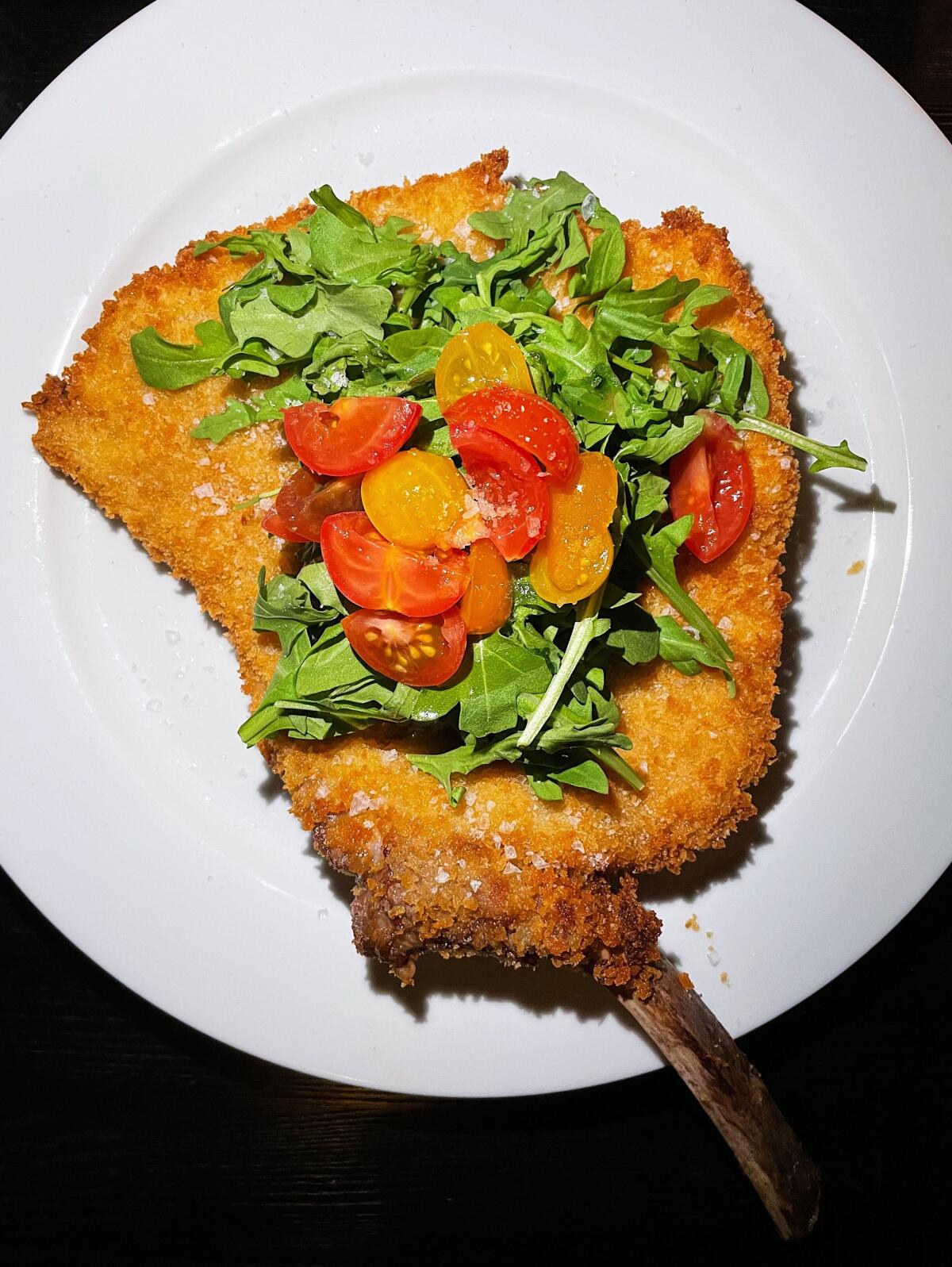 Cotoletta alla Milanese, a breaded veal chop with arugula and tomatoes, at Dal Milanese.
