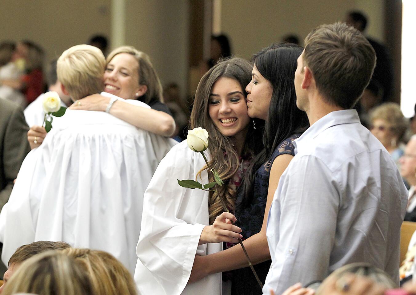 Cailin Sauser, center, gives her mom Lisa a white rose as a gesture of appreciation with her dad Chris, during Mariners Christian School 2013 eighth-grade commencement ceremony at St. Andrews Church in Newport Beach on Thursday.