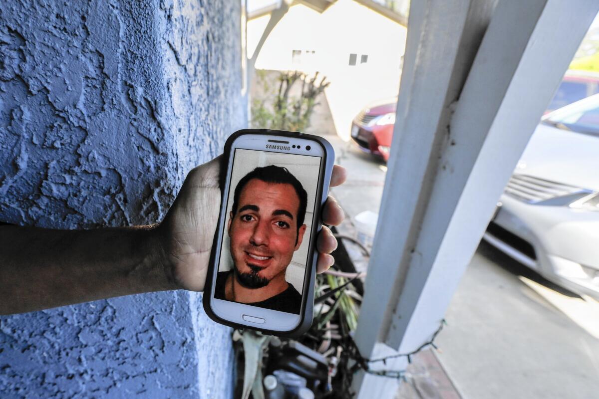 Next-door neighbor Maria Gomez holds her phone displaying a photo of Amier Issa, who was allegedly killed by his father at the family's North Hills home last week.
