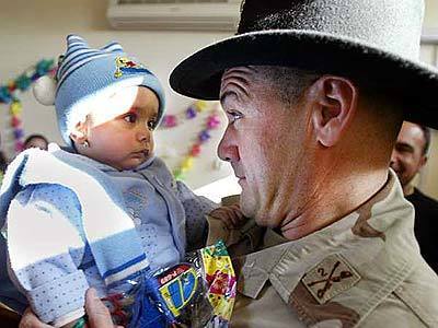 U.S. Army 2nd Armored Calvary Regiment Lt. Col. Mark Calvert holds Benin Raad, an Iraqi baby, during a New Year 's Eve party for orphans and poor children in Baghdad.