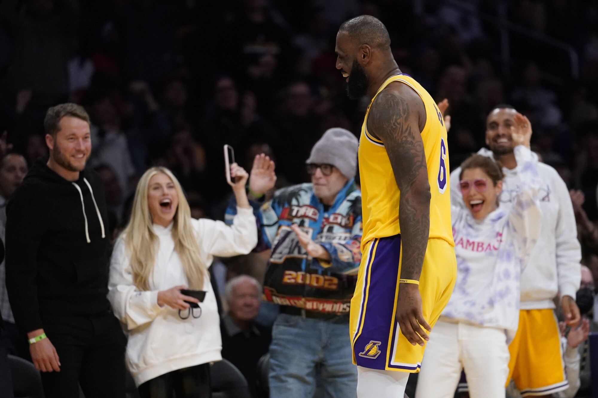 Lakers forward LeBron James walks back to the bench in front of Rams quarterback Matthew Stafford, left, and his wife, Kelly.