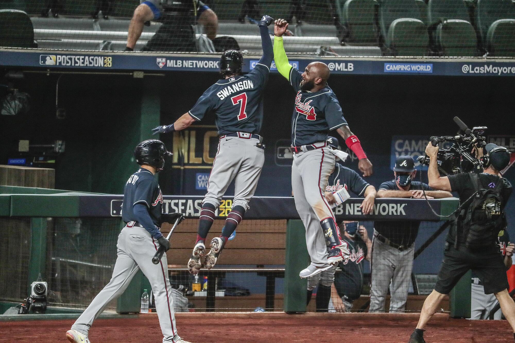 Marcell Ozuna and Dansby Swanson leap into the air for a forearm bump.