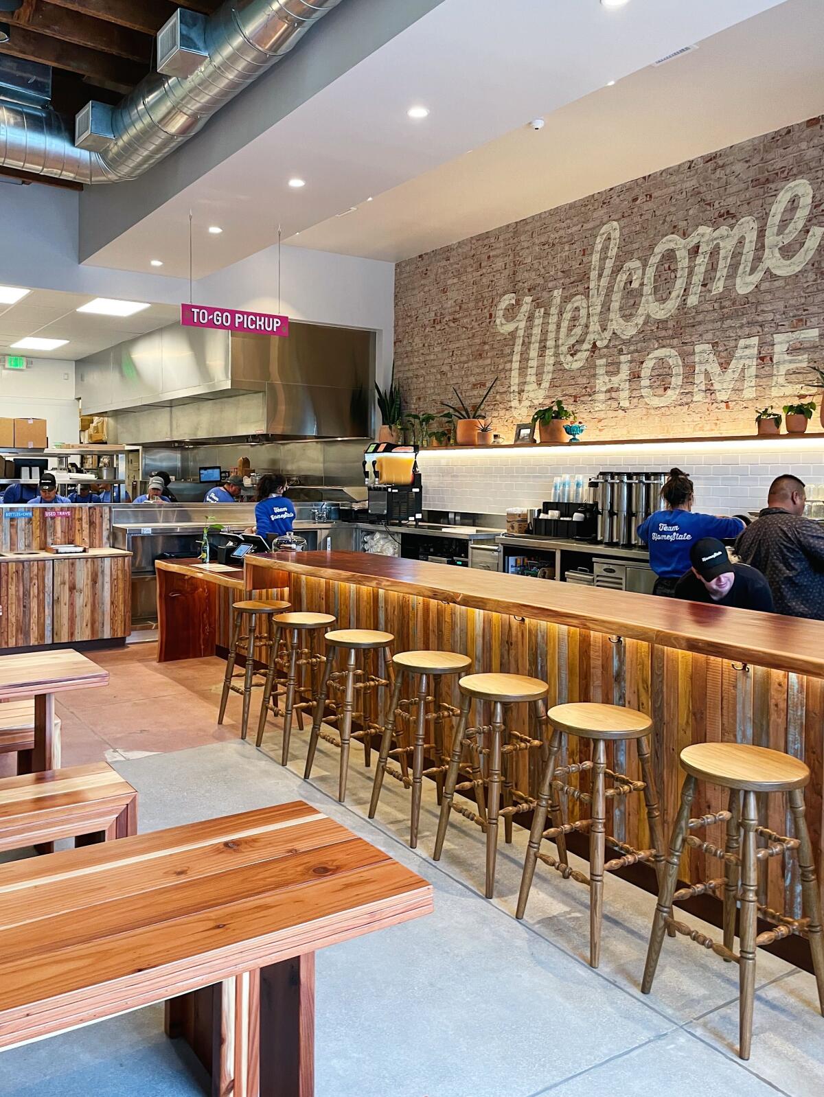A vertical interior photo of the Atwater Village HomeState. Behind the bar a sign reads "Welcome Home."