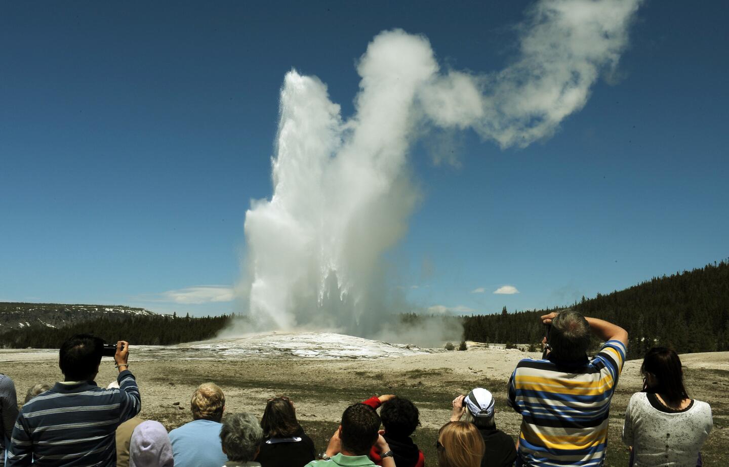 Tourists watch Old Faithful, a large geyser that erupts on average every 90 minutes, in Yellowstone National Park. The park, established in 1872, is primarily in Wyoming, though it also extends into Montana and Idaho. It was the first national park in the United States.