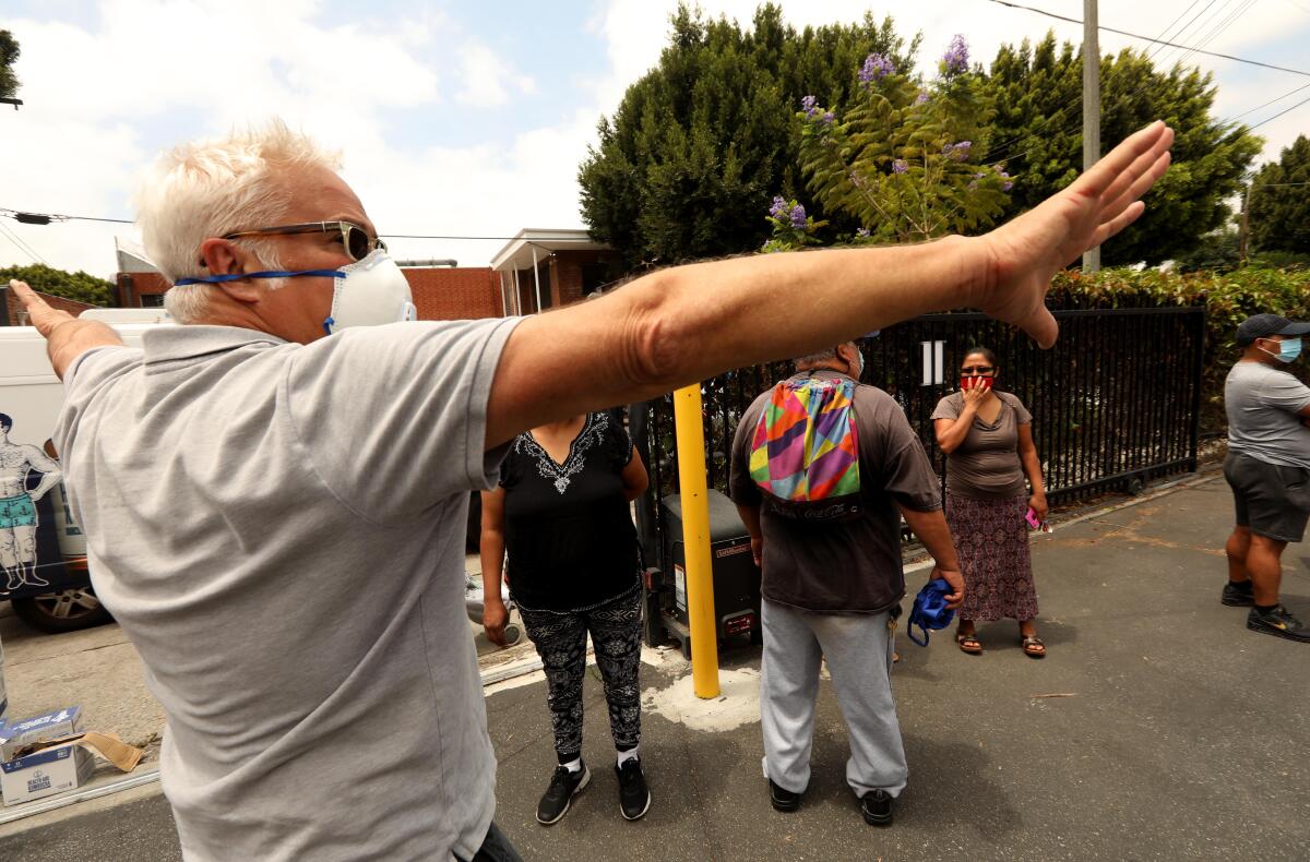  Craig Taubman directs people to wait in a line for a food giveaway for needy residents at the Pico Union Project.