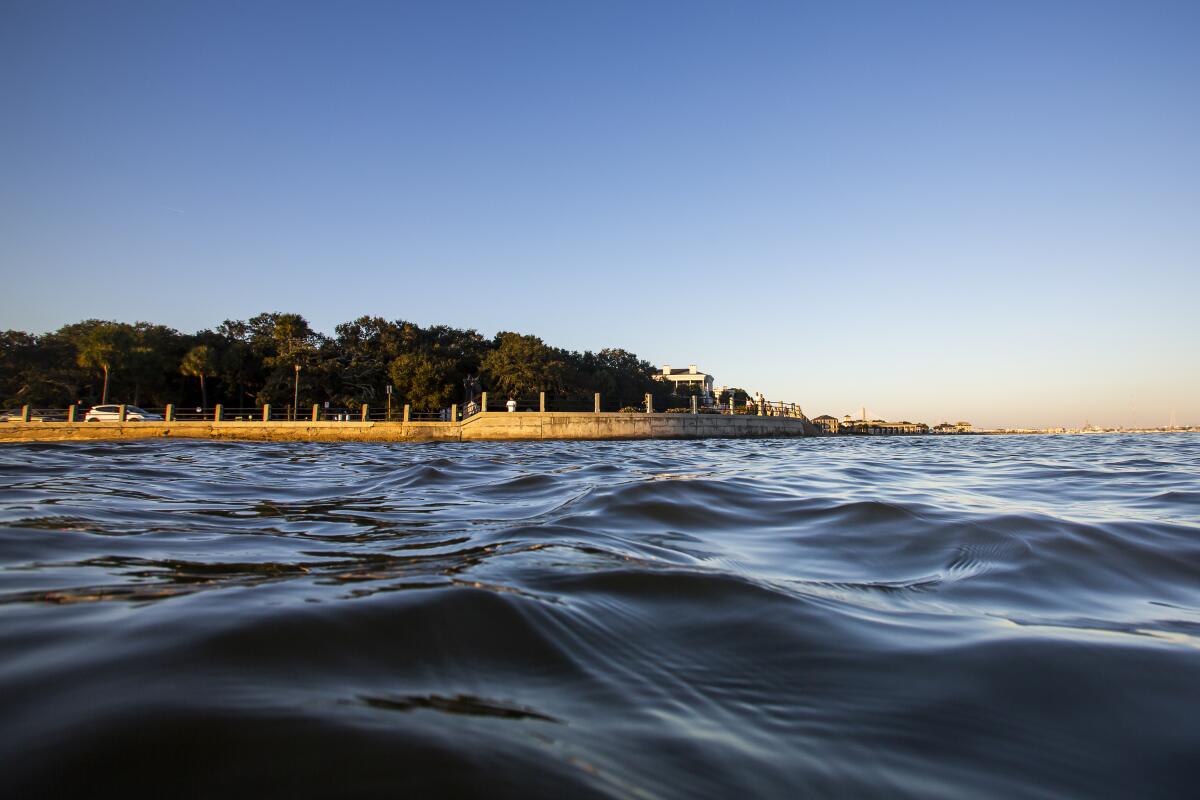 As high tide laps against the sea wall tourist walk down the Battery in Charleston, S.C.