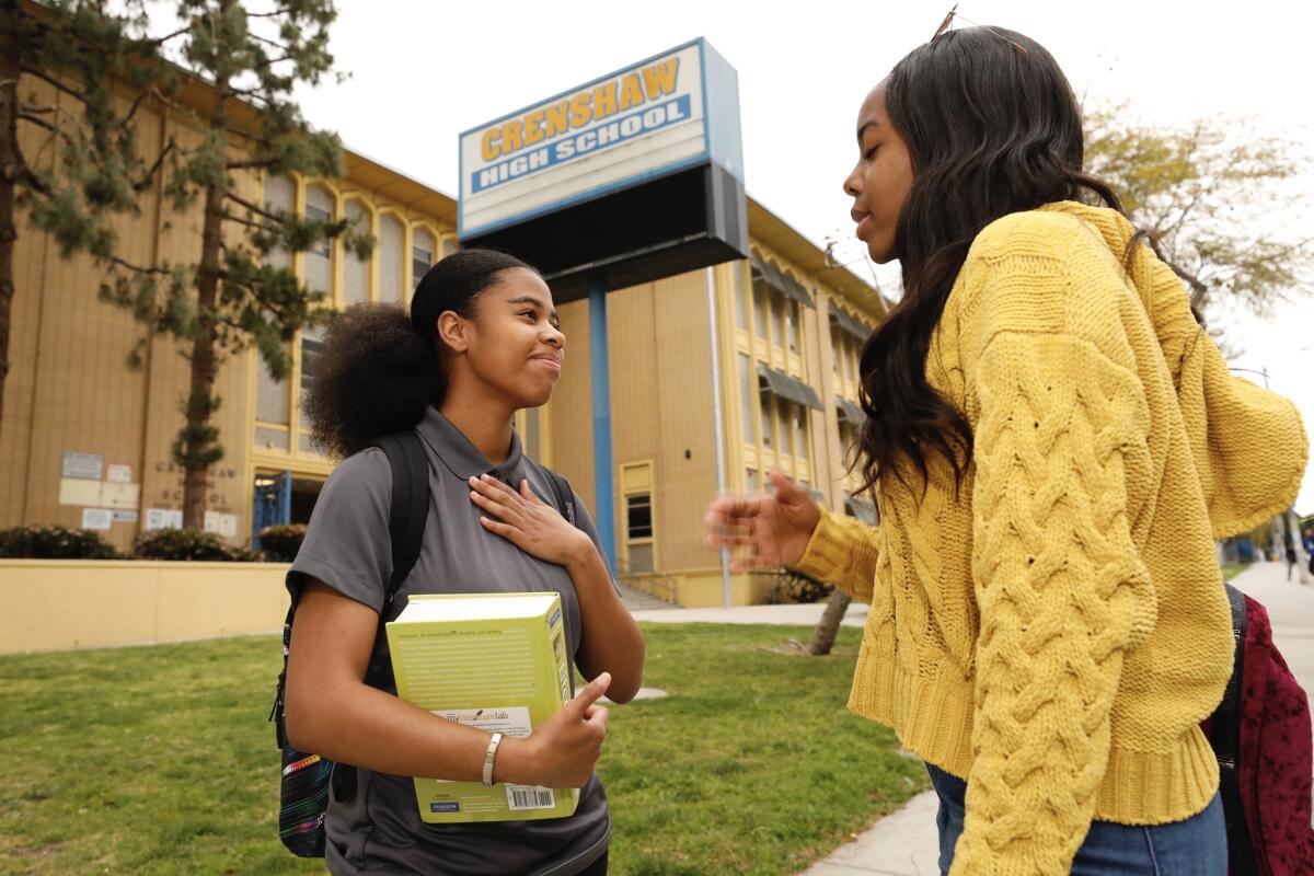 Kaya Buckley, left, and Kaelyn Campbell, both seniors at Crenshaw High School, talk before heading to class Thursday morning. The campus is just blocks from where rapper Nipsey Hussle was shot and killed.