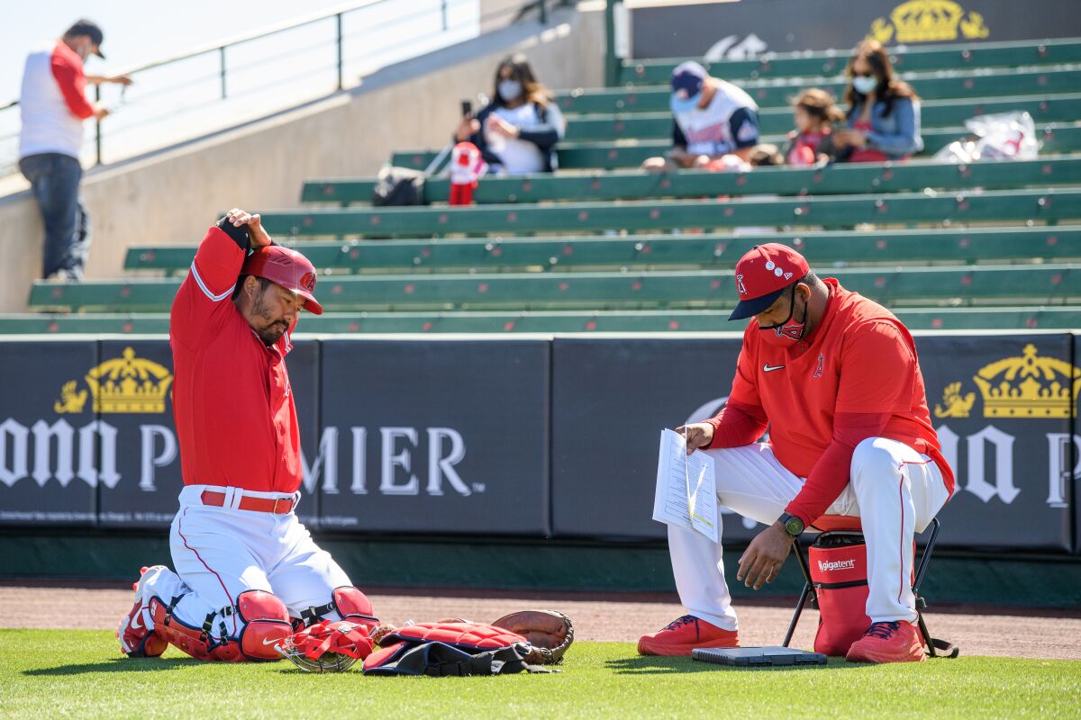 Angels catcher Kurt Suzuki stretches next to catching coach Jose Molina before a spring training game.