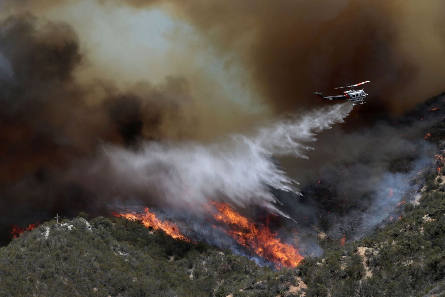 A tanker helicopter makes a drop as crews work to protect a handful of homes from the Powerhouse fire burning near Castaic.