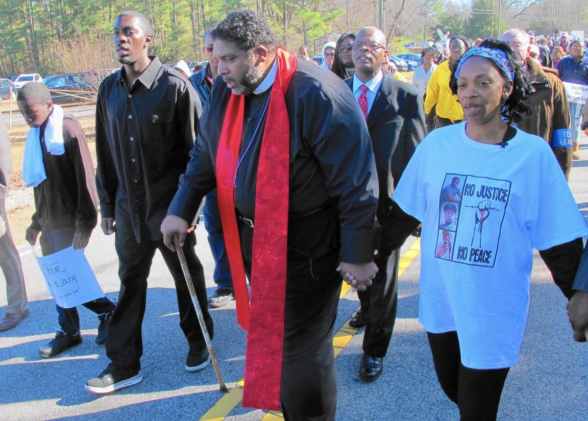 Claudia Lacy, mother of teenager Lennon Lacy, marches with the Rev. William J. Barber II, president of the North Carolina NAACP, center, and Pierre Lacy, Lennon's brother. Lennon's death in August was ruled a suicide, but the family has sought further inquiry.